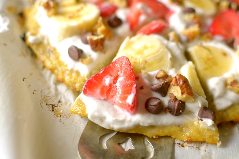 This Healthy Banana Bread Fruit Pizza is a delicious dessert, breakfast or snack! It has a banana bread-like crust and is topped with a strawberry cream cheese frosting, fruit, nuts and chocolate. It is completely gluten-free, paleo and has a vegan option!